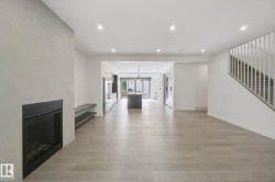 Light wood-finish flooring, recessed lighting, and a modern fireplace with a black surround - 