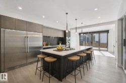 Gourmet kitchen with stainless steel appliances, a large island with seating, a dark tile backsplash, and light wood-finish flooring - 