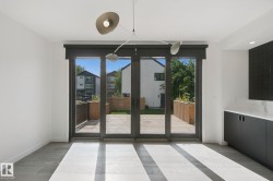Full-light sliding glass doors, contemporary overhead lighting, wood-finish flooring, and built-in cabinetry with a light-toned countertop - 
