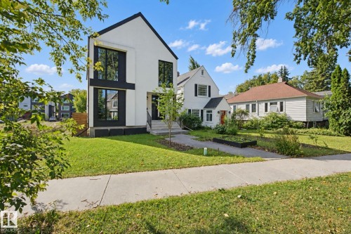 Modern exterior with a white facade and black trim, large windows, a front lawn, and a concrete walkway - 10925 University Avenue Nw, Edmonton, AB 