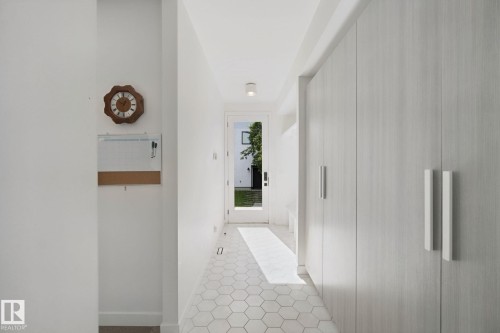 Hexagonal tile flooring, full-height built-in cabinetry with modern pulls, and a glass-paneled exterior door - 10925 University Avenue Nw, Edmonton, AB 