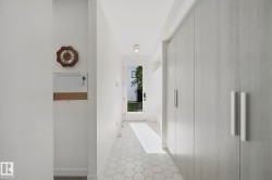 Hexagonal tile flooring, full-height built-in cabinetry with modern pulls, and a glass-paneled exterior door - 