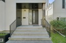 Concrete steps with metal railings leading to an entryway featuring a dark wood-finish ceiling, a modern front door with vertical glass insert, and an exterior wall sconce - 10925 University Avenue Nw, Edmonton, AB 