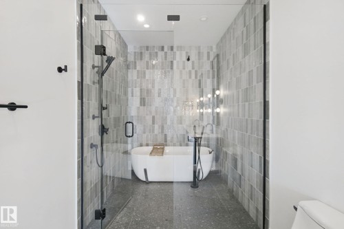 Glass-enclosed shower with matte black hardware, a freestanding bathtub, and floor-to-ceiling tile - 10925 University Avenue Nw, Edmonton, AB 