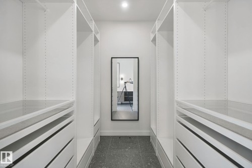 Custom closet system featuring white shelving, integrated drawers, and a full-length mirror - 10925 University Avenue Nw, Edmonton, AB 