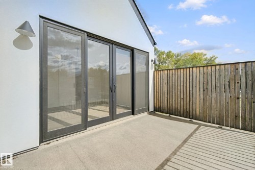 Concrete patio with a wood-plank privacy fence and modern exterior lighting - 10925 University Avenue Nw, Edmonton, AB 