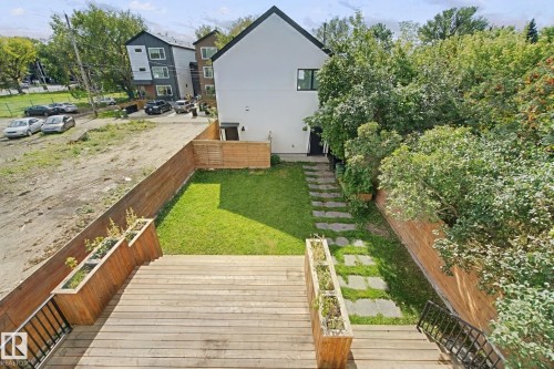 Wood-finish deck with integrated planters, expansive green lawn, stone paver pathway, and private fencing - 10925 University Avenue Nw, Edmonton, AB 