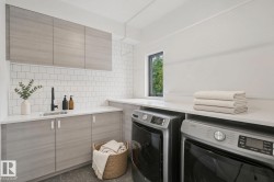 Laundry area featuring light wood-finish cabinetry, white subway tile backsplash, a sink with a black faucet, and a light-colored countertop - 