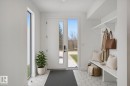 Entryway featuring white hexagonal tile flooring, a white paneled entry door with vertical glass inserts, a full-length sidelight, and a built-in bench with integrated shelving and coat hooks - 10925 University Avenue Nw, Edmonton, AB 