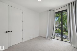 White walls, light carpet flooring, large window, full-height curtains, and double closet doors with dark hardware - 