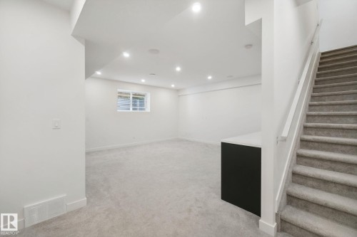 Expansive carpeted area with recessed lighting, a built-in window, and a sleek dark base with a light countertop - 10925 University Avenue Nw, Edmonton, AB 