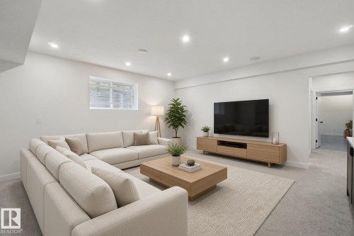 Recessed lighting illuminates the open living area featuring light-toned carpeting and a built-in media console - 10925 University Avenue Nw, Edmonton, AB 