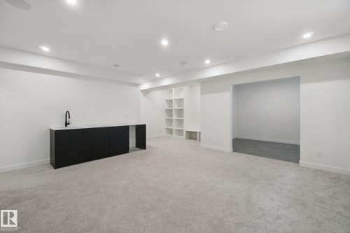 Recessed lighting, light gray carpeting, built-in shelving, black cabinetry with countertop, and a matte black faucet - 10925 University Avenue Nw, Edmonton, AB 