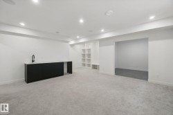 Recessed lighting, light gray carpeting, built-in shelving, black cabinetry with countertop, and a matte black faucet - 