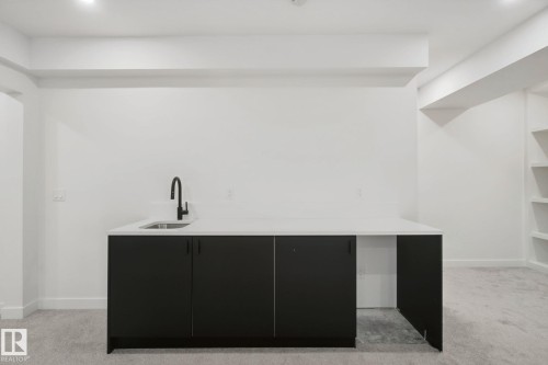 Built-in wet bar with a stainless steel sink, matte black faucet, and white countertop - 10925 University Avenue Nw, Edmonton, AB 