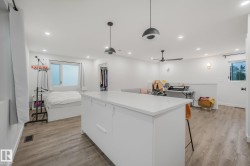 Open-concept living space with wood-finish flooring, recessed lighting, and a white kitchen island - 