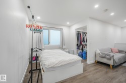 Recessed lighting illuminates the space, featuring wood-finish flooring and a window with white trim - 