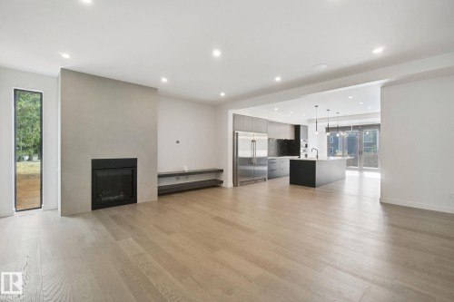 Wood-finish flooring, recessed lighting, and a linear fireplace with a built-in media shelf - 10925 University Avenue Nw, Edmonton, AB 
