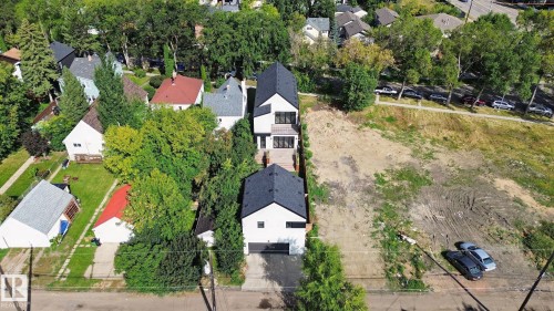 Modern residential structure with a black-pitched roof and light-colored siding, featuring multiple balconies and an attached two-car garage - 10925 University Avenue Nw, Edmonton, AB 