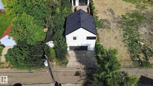 Modern facade with a dark shingle roof, attached garage, and surrounding mature trees - 10925 University Avenue Nw, Edmonton, AB 