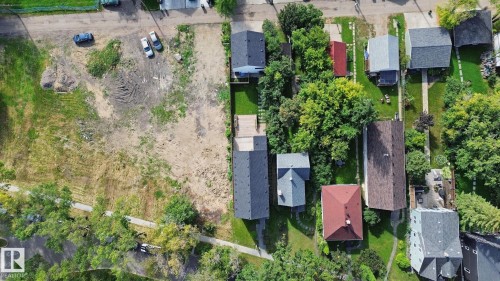 Cleared lot with existing paved road access, surrounded by mature trees, and existing utility poles - 10925 University Avenue Nw, Edmonton, AB 