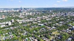 Urban landscape with a prominent city skyline, residential areas featuring mature trees, and a river winding through the expanse - 