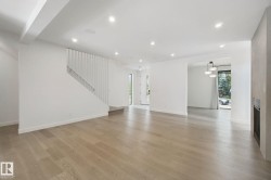 Open concept living space featuring wide plank wood-finish flooring, recessed lighting, a modern staircase, and a built-in fireplace - 