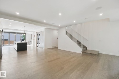 Open-concept layout with wood-finish flooring, recessed lighting, and a modern stair railing - 10925 University Avenue Nw, Edmonton, AB 