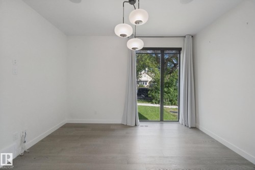 Wood-finish flooring, white walls, and a contemporary multi-globe pendant light fixture - 10925 University Avenue Nw, Edmonton, AB 