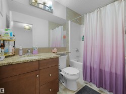 Bathroom featuring a vanity with wood-finish cabinetry, a stone-finish countertop, and an integrated sink - 