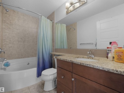 Built-in vanity with a granite-style countertop, undermount sink, and wood-finish cabinetry - #40 2003 Rabbit Hill Rd Nw, Edmonton, AB 