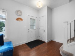 White entry door with frosted glass panel, wood-finish flooring, and white trim - 