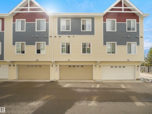 Multi-level townhome exterior featuring siding in varied tones, multiple windows, and integrated garage doors - #40 2003 Rabbit Hill Rd Nw, Edmonton, AB 