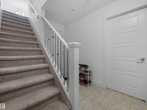Carpeted staircase with white newel post and metal balusters - #40 2003 Rabbit Hill Rd Nw, Edmonton, AB 