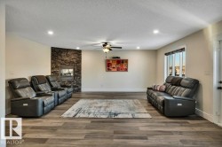 Living area featuring wood-finish flooring, a stone-accented fireplace, recessed lighting, a ceiling fan, and a window with exterior visibility - 