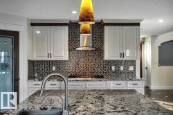 Kitchen island with a stainless steel undermount sink, gooseneck faucet, and mottled countertop - 