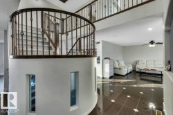 Curved staircase featuring ornate wrought iron balusters and a dark wood handrail - 