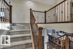 Carpeted staircase with wood-finish handrails and decorative metal spindles - 