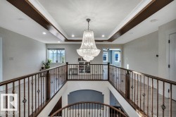 Grand two-story foyer featuring an ornate crystal chandelier and a coffered ceiling with dark wood accents - 