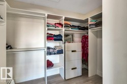 Custom closet system featuring multiple hanging rods, integrated shelving, and a built-in chest of drawers with gold-tone hardware - 