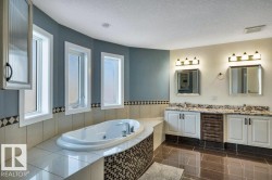 Soaking tub with mosaic tile surround, complemented by three vertical windows - 
