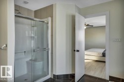 Bathroom featuring a glass-enclosed shower with tile surround and dark tile flooring - 