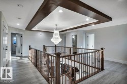 Upper floor landing featuring a coffered ceiling with recessed lighting and a central chandelier - 