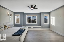 Spacious interior with wood-finish flooring, a contemporary ceiling fan, three windows with arch-top grilles, a built-in window bench, and wall sconces - 