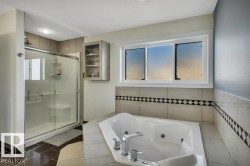 Soaking tub with chrome fixtures, surrounded by neutral tile with a decorative accent band - 