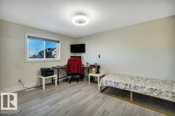 Spacious room featuring light wood-finish flooring, a bright window with white trim, a flush-mount ceiling light fixture, and neutral painted walls - 