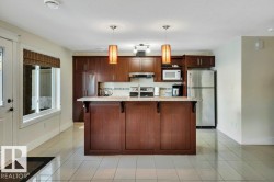 Kitchen featuring an island with a light-toned countertop, integrated double sink, and dark wood-finish cabinetry - 