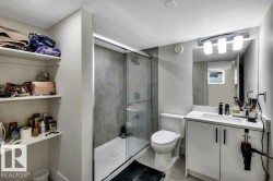Modern bathroom featuring a glass-enclosed shower with textured wall tile, a single vanity with white cabinetry, a rectangular sink, and a large wall mirror - 