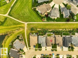 Aerial perspective showcasing residential properties bordering a linear park with walking paths and green spaces - 