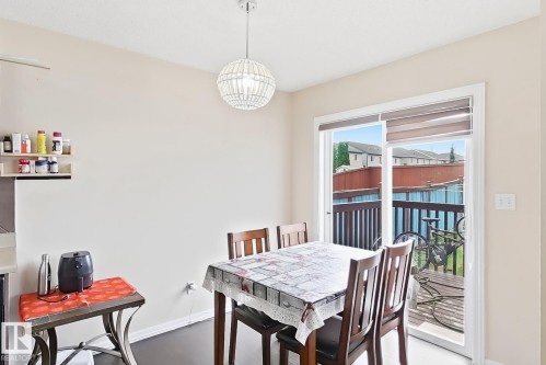 Sliding glass door access to an outdoor deck, overhead pendant lighting, and dark wood-finish flooring - 2829 18A Avenue Nw, Edmonton, AB 